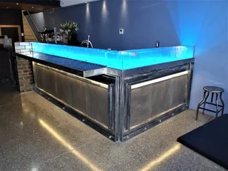 Metal bar counter with illuminated blue glass surround
