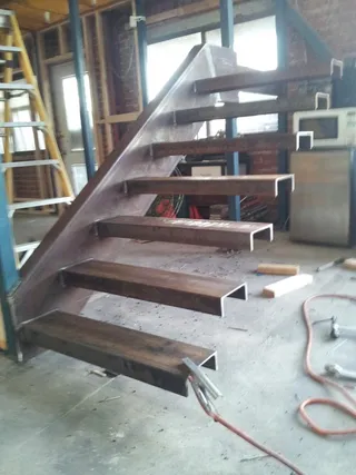 Raw steel staircase frame being fabricated indoors